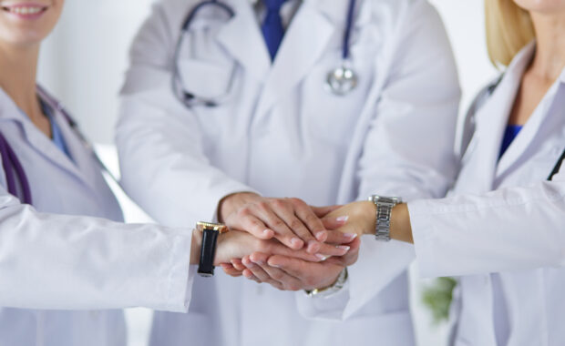 Doctors and nurses in a medical team stacking hands.